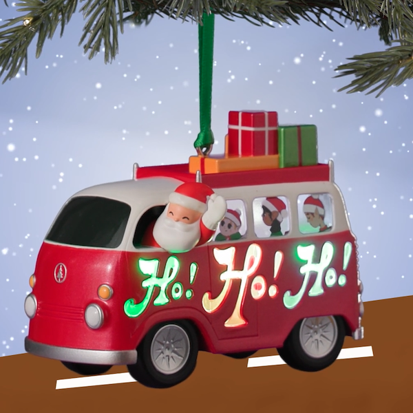 A Keepsake Ornament in the shape of a VW microbus, driven by Santa Claus and filled with elves, with wrapped presents strapped to the roof.
